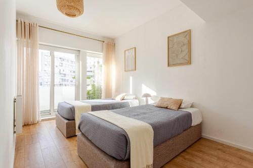 two beds in a room with a window at Serpa Downtown Gaia in Vila Nova de Gaia