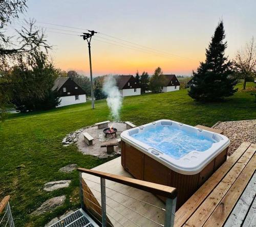 a hot tub sitting on a deck next to a fire pit at Čistá v Krkonoších - Chata Belmonda in Cerny Dul
