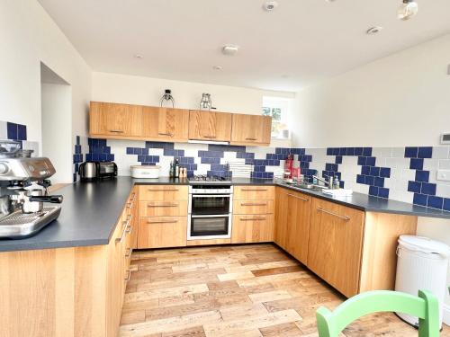 a kitchen with wooden cabinets and blue and white tiles at 3 bedroom stunning house with garden and amazing sea views in Dartmouth