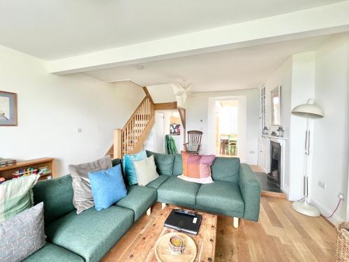 a living room with a green couch with colorful pillows at 3 bedroom stunning house with garden and amazing sea views in Dartmouth