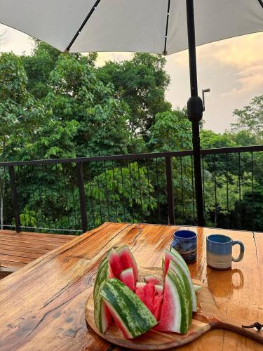 a plate of fruit on a wooden table with an umbrella at Maze Lodge in Puerto Jiménez