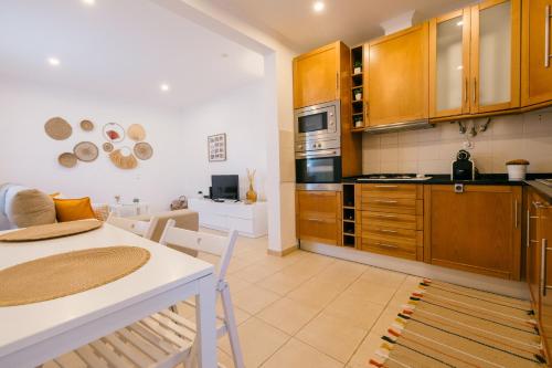a kitchen with wooden cabinets and a white table and chairs at Tree House - Casa Laranjeira in Quinta do Conde
