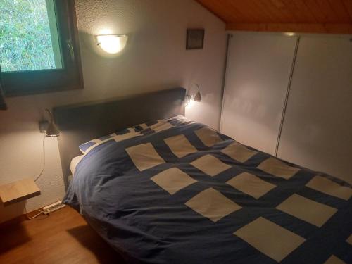 une chambre avec un lit avec une couverture bleue et blanche dans l'établissement Le Ciel Bleu, à Châtel