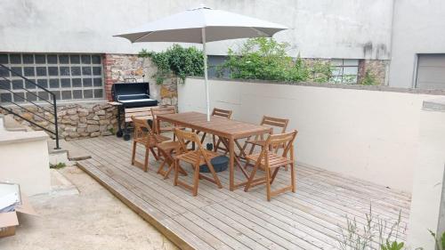 a wooden table and chairs with an umbrella on a patio at La Maison d Elodie in Vierzon