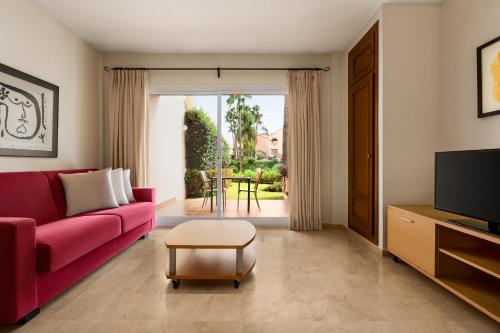 a living room with a red couch and a table at Wyndham Grand Costa del Sol in Mijas Costa