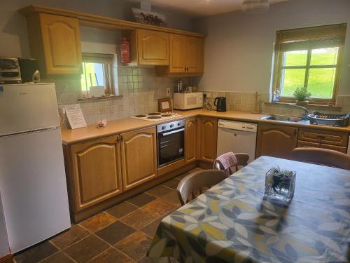 a kitchen with wooden cabinets and a table with a table sidx sidx sidx at Kearneys Cottage, Dugort, Achill Island, County Mayo - 3 Bedroom Sleeps 6 in Bellanasally