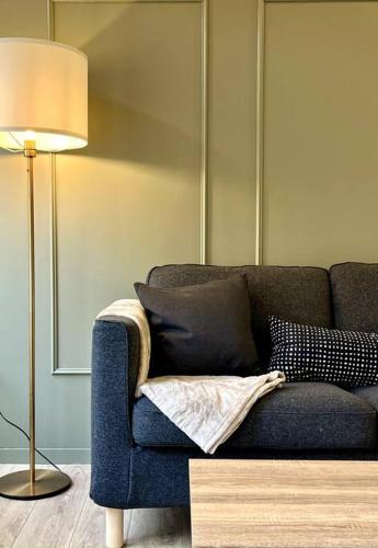 a living room with a blue couch and a lamp at Le Troglochill in Belvès