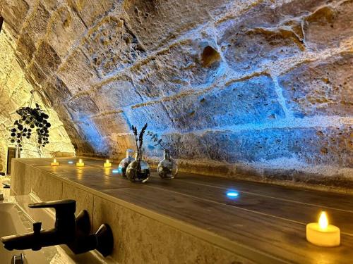 a stone wall with candles on a shelf in a room at Le Troglochill in Belvès