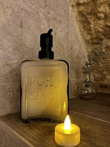 a bottle of pure soap with a candle on a table at Le Troglochill in Belvès