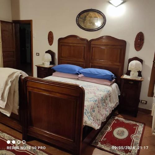 a bedroom with a large wooden bed with blue pillows at Villa Cipressi del 1800 appartamento 7 posti letto in Ruina