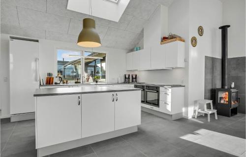 a kitchen with white cabinets and a fireplace at Nice Home In Bogense With Wifi in Bogense