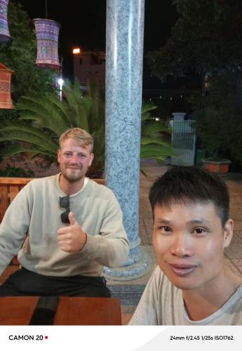 a man giving a thumbs up next to a young boy at Night Market Heart Hotel MC in Mộc Châu