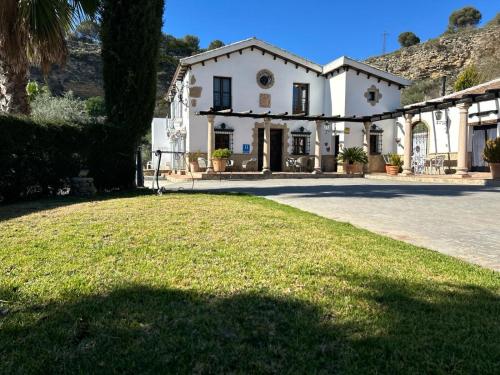a large white house with a lawn in front of it at Hotel Rural Hacienda de Ronda in Ronda