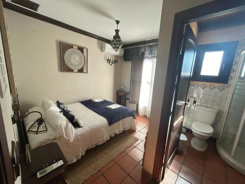 ロンダにあるHotel Rural Hacienda de Rondaのベッドのある寝室とシャワー付きのバスルーム