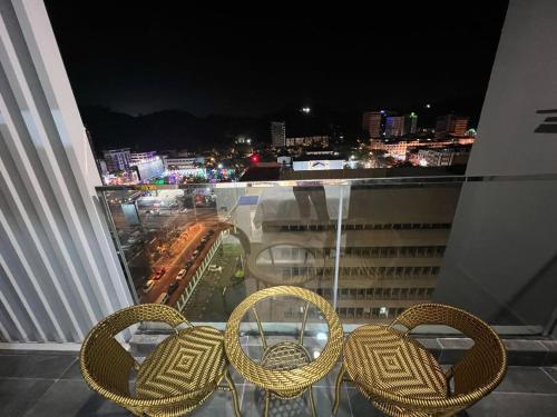 three rattan chairs sitting on a balcony at night at Bian's Cozy Suite in Kota Kinabalu