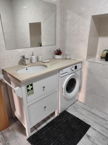 a bathroom with a sink and a washing machine at CASA do AÇÔR in Aldeia das Dez