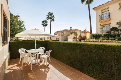 a patio with a table and chairs and an umbrella at Ramada Hotel & Suites by Wyndham Costa del Sol in Fuengirola