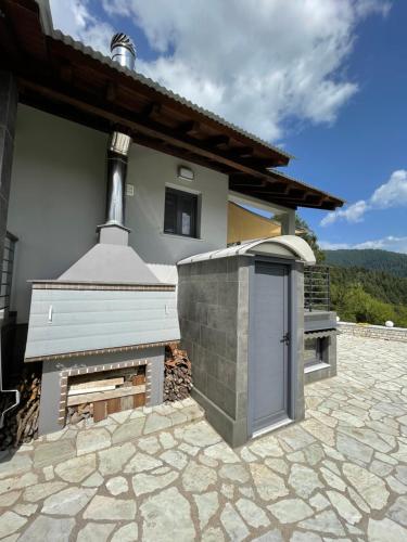 a house with a brick fireplace next to a building at Marosa Guesthouse in Tríkala