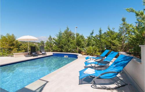 a swimming pool with blue chairs and an umbrella at Gorgeous Apartment In Selca With Wifi in Selca