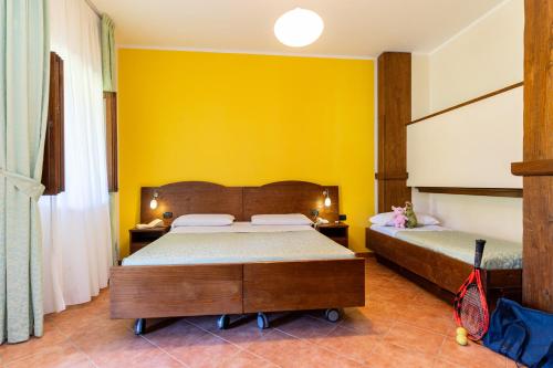 a bedroom with two beds and a yellow wall at Hotel Masseria Le Pajare in Presicce