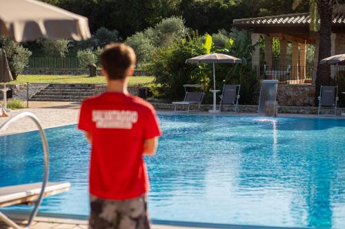 a young boy standing in front of a swimming pool at Hotel Masseria Le Pajare in Presicce