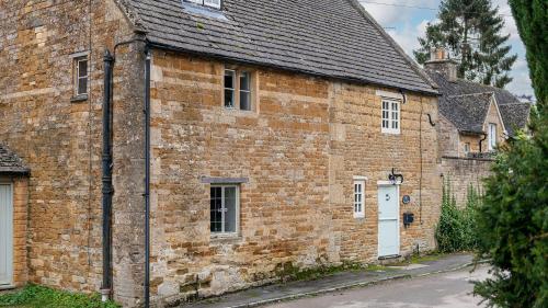 an old brick building with a white door at Wyck Cottage in Bourton on the Water