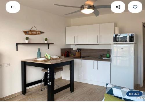 une cuisine avec des armoires blanches et une table à l'intérieur dans l'établissement Studio direct plage, au Lavandou