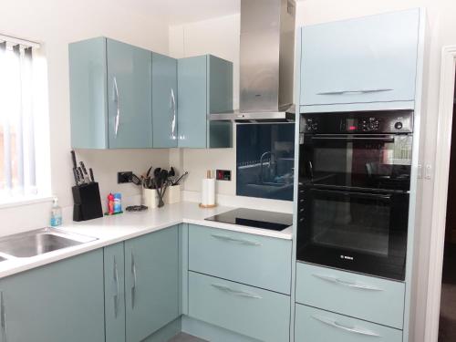 a kitchen with white cabinets and black appliances at Belle Vue Guesthouse in Glastonbury