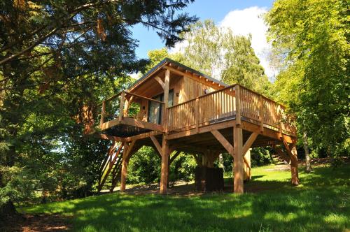 a tree house with a deck in the grass at Lodges Arverne in Vic-le-Comte