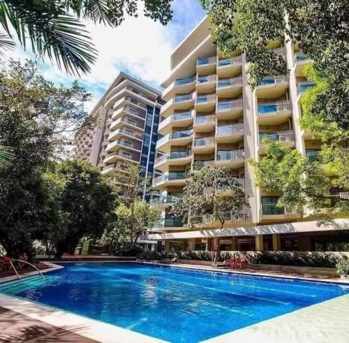 a swimming pool in front of a large building at Tambuli 1 Bedroom Beachfront Condo in Lapu Lapu City