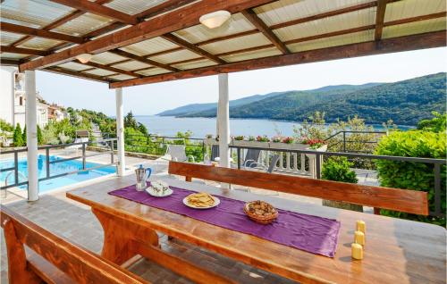 a wooden table on a patio with a view of the water at 4 Bedroom Beautiful Home In Rabac in Rabac