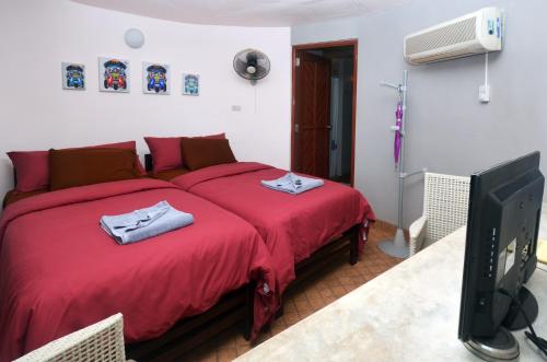 - une chambre avec un lit rouge et une télévision dans l'établissement Koh Mak Buri Hut Natural Resort, à Ko Mak