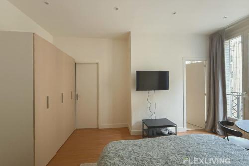 une chambre avec un lit et une télévision au mur dans l'établissement Flexliving - Dardanelles - Studio, à Paris