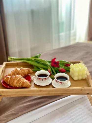 a tray with two cups of coffee and croissants and flowers at Malina Residence Aparthotel in Cisnădie