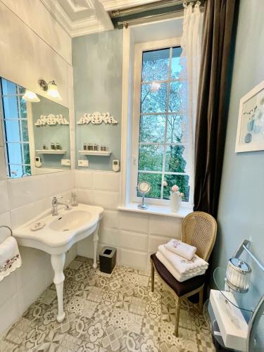 une salle de bain blanche avec un lavabo et une fenêtre dans l'établissement Le Château de Fresnoy en Gohelle, à Fresnoy-en-Gohelle