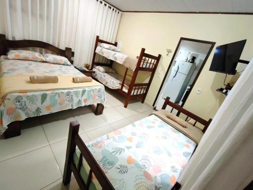 a bedroom with a bed and two chairs and a mirror at Chalé da cachoeira - Ilhabela in Ilhabela
