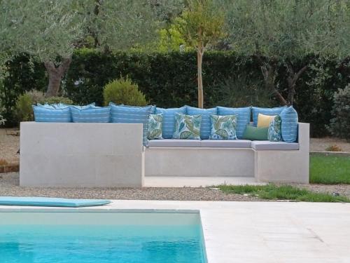 a couch with pillows on it next to a pool at I MURETTI A SECCO B&B in Castel del Monte