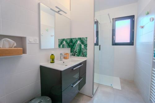 une salle de bain blanche avec lavabo et douche dans l'établissement La contemporaine 2 chambres à Ste Marie, à Sainte-Marie-la-Mer