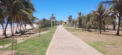 a walkway along a beach with palm trees at Fantástica Casa 03 Quartos nas belíssimas Praias do Flamengo in Salvador