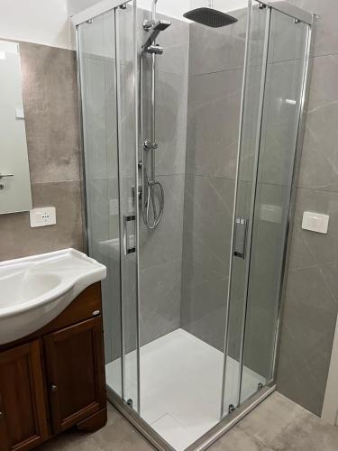 a shower with a glass door next to a sink at Falaride suite Agrigento discesa sulla valle di oro in Agrigento