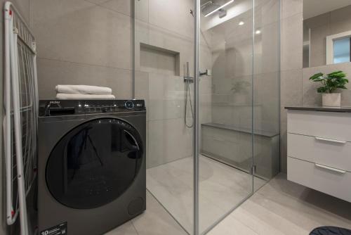 a washing machine in a bathroom with a shower at Aparts4U - Kras Resort Apartament A103 z prywatnym jacuzzi i widokiem na góry in Szklarska Poręba