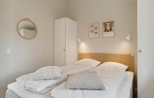 a bedroom with a bed with white sheets and a mirror at Stunning Home In Blåvand With Sauna in Blåvand