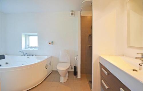 a bathroom with a tub and a toilet and a sink at Holiday Home Fiskervej Thisted Iii in Nørre Vorupør