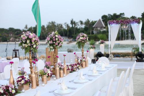 a long table with white chairs and flowers on it at Mithi Resort & Spa in Panglao