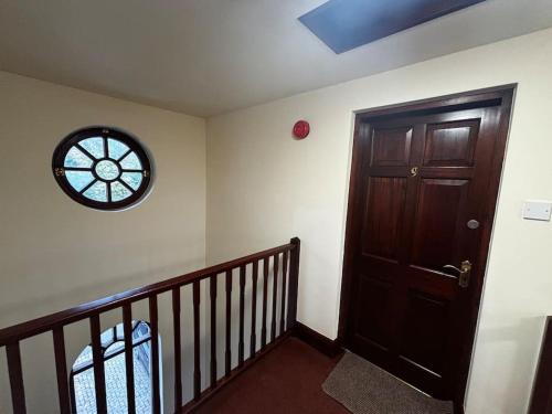 a hallway with a wooden door and a clock on the wall at Dovera, private parking included, Bowness on Windermere in Bowness-on-Windermere