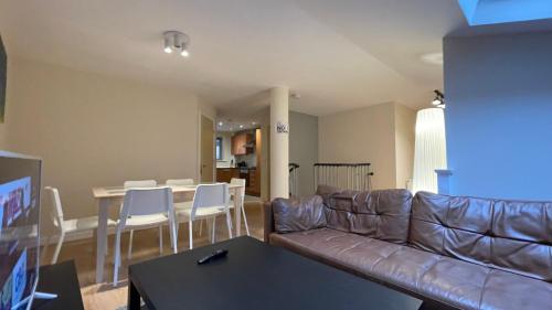 a living room with a leather couch and a table and chairs at 4- bedroom , 1 living room Apartment Near Emirates Stadium in London
