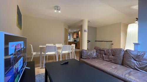 a living room with a brown leather couch and a table at 4- bedroom , 1 living room Apartment Near Emirates Stadium in London