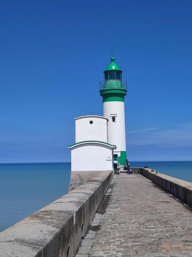 a green and white lighthouse sitting on a pier at La Perle in Mers-les-Bains