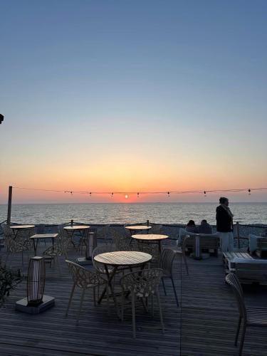 a group of tables and chairs on the beach at sunset at La Perle in Mers-les-Bains