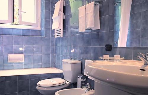 a blue tiled bathroom with a toilet and a sink at Pràti Home in Rome